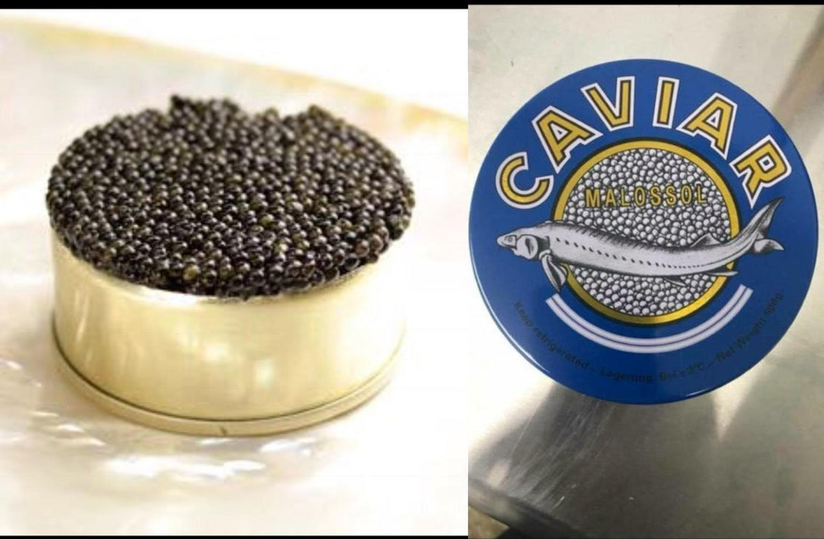 Kaluga black caviar in an open gold tin beside the blue Caviar Malossol tin lid