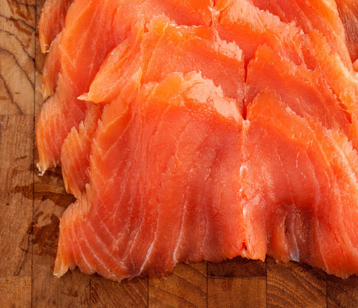 Fresh-sliced lox fanned out on a wooden board