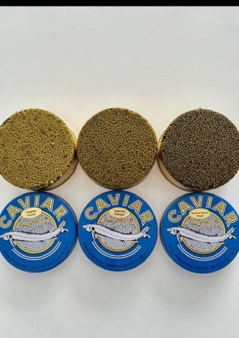 Three open caviar tins above their labeled blue lids